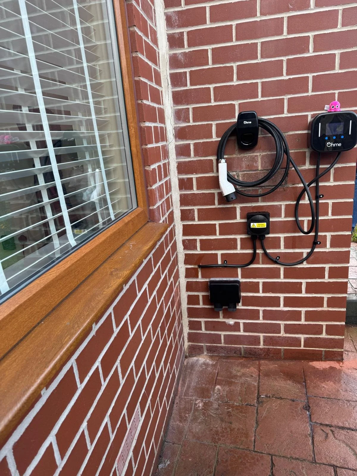 Wall-mounted Ohme Smart EV Charger with built-in interactive LCD screen display.